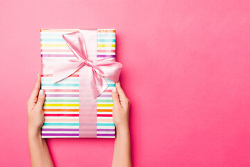 Girl Hands holding craft paper gift box with as a present for Christmas or other holiday on pink...