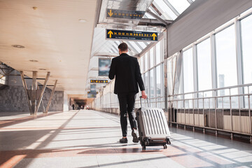 Man carrying his luggage through the airport - obrazy, fototapety, plakaty