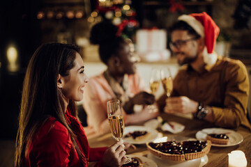 Happy woman drinking Champagne while celebrating Christmas with her friends at home.