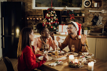 Group of happy friends eating dessert and talking during Christmas dinner at home.