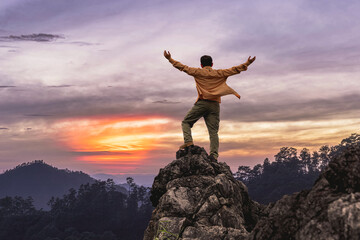 Success male hiker with arms outstretched on top of mountain