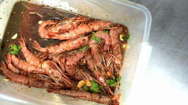 Shrimps with soy sause, garlic, parsley in plastic box. Chef mixes shrimps. HD