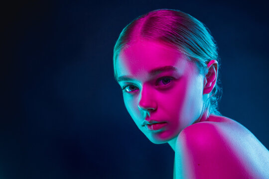 Tender. Portrait of female fashion model in neon light on dark studio background. Beautiful caucasian woman with trendy make-up and well-kept skin. Vivid style, beauty concept. Close up. Copyspace