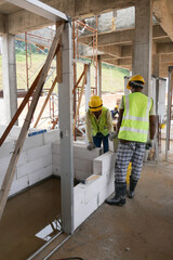 Fototapeta premium SEREMBAN, MALAYSIA -MARCH 16, 2020: Construction workers laying autoclaved aerated concrete block at the construction site. The use of this material can save time and facilitate construction work.