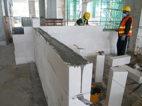 SEREMBAN, MALAYSIA -MARCH 16, 2020: Construction workers laying autoclaved aerated concrete block at the construction site. The use of this material can save time and facilitate construction work.
