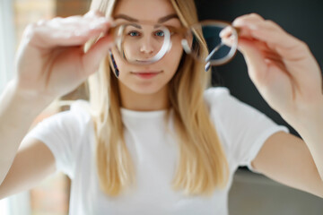 A woman has vision problems, squints when trying to see something, takes off her glasses, is isolated. Myopia, hyperopia, vision concept. High quality photo.