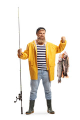 Full length portrait of a fisherman in a yellow rain coat holding a fishing pole and fish
