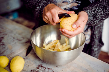Pealing potatoes in a metal bowl on a rustic table in Spain
