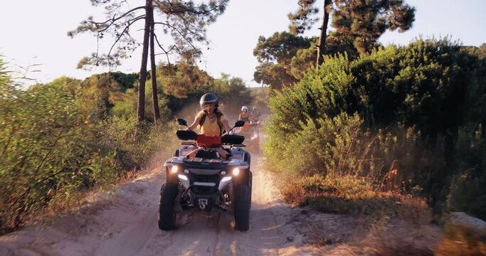 Group of friends riding quad bikes together on sand road