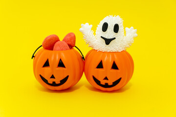 Halloween pumpkins with candy and ghost, yellow background