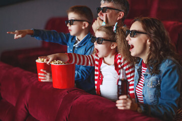 Family mom father and children are watching a projector, TV, cinema, movies with popcorn in the cinema. High quality photo.