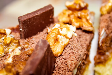 Close-up of the top of a chocolate cake decorated with chocolate slices and walnuts with cocoa.
