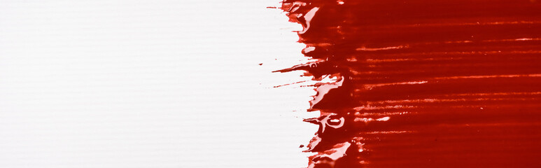 top view of colorful red paint brushstroke on white background