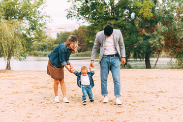 Obraz premium Family walking and having a great time together on sand in park near a lake
