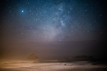 night view of a rocky beach with stars