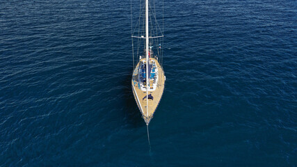 Aerial drone top down photo of beautiful wooden sailboat anchored in Aegean deep blue sea near...