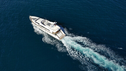 Aerial drone photo of luxury yacht with wooden deck cruising deep blue Aegean sea near island of Mykonos, Cyclades, Greece