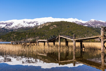 Scene view of old wooden pier against snow-capped Andes mountains in Green Lake (Lago Verde) in Los Alerces National Park, Patagonia, Argentina