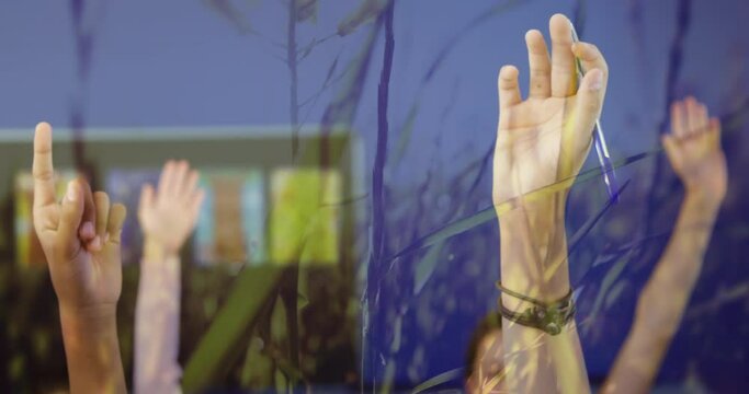 Group of students raising hands in class against grass