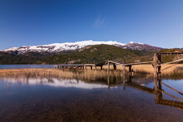 Scene view of old wooden pier against snow-capped Andes mountains in Green Lake (Lago Verde) in Los Alerces National Park, Patagonia, Argentina