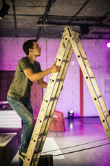Theater lighting technician electric engineer adjusting focus of lighting elements backstage....