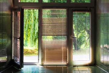 Glass windows and doors with shutters, exit from the building to the green summer garden