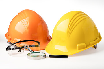 Yellow and orange construction helmet, safety glasses and magnifying glass isolated on white background with clipping path, engineer concept.