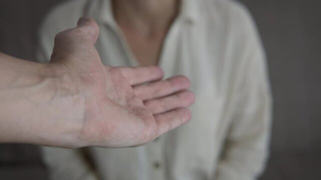 Man gives his hand and help. A woman takes the man's proffered hand in the room.