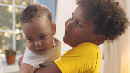 Close up portrait of african boy hugging and kissing newborn brother