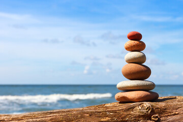 Zen pyramid of balanced stones on a background of the summer sea and blue sky