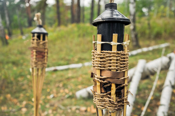 Torch with wick in the forest prepared to ignite. Felled trees and green grass on the background.