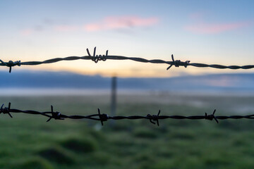 Stacheldraht mit Sonnenuntergang im Hintergrund