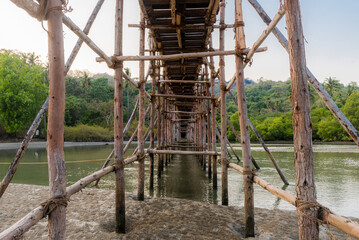 Fototapeta na wymiar Wooden bridge with poles-props across the river in the jungles of India