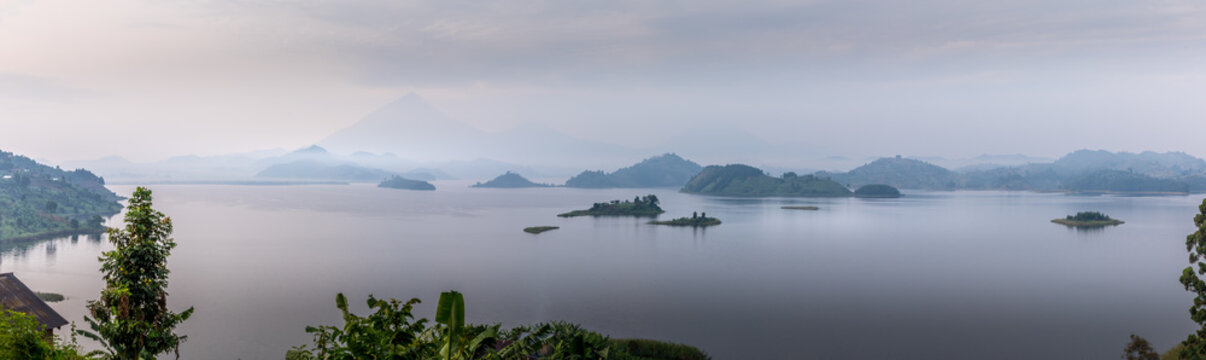 Panorama of Lake Mutanda at morning with view on the volcanoes mount Muhavuru and mount Gahinga in East Africa, along the border of Rwanda and Uganda.	