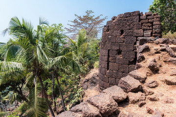 Obraz premium View of the old stone tower of the Portuguese fortress Fort Cabo De Rama in the rainforest in Goa, India
