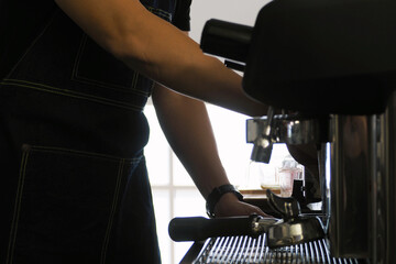Professional barista in process of making fresh coffee using the machine at his cafe. Barista working lifestyle and coffee brewing process concept