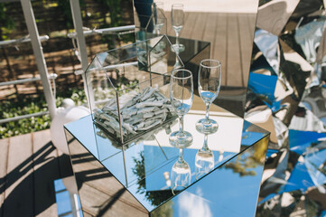 Wedding decorations: an arch made of shiny foil, a mirror stand, glass goblets, a box with papers, money, surprises.