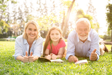 Parents and daughters are reading in the lawn at the weekend. A family reading on the grass.