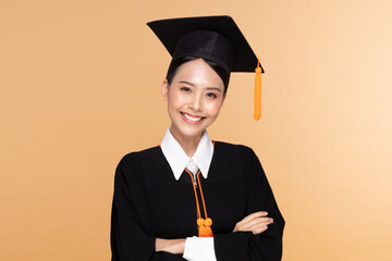 Beautiful Attractive Asian woman graduated in cap and gown smile so proud and happiness,Isolated on Beige background,Education Success Concept