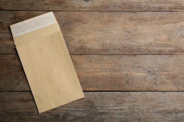 Kraft paper envelope on wooden background, top view. Space for text