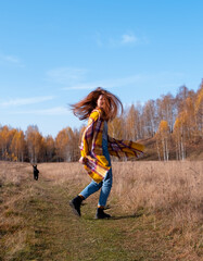red-haired girl with a dog runs through the autumn forest
