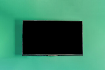 modern led tv screen with black empty space for mockup hanging on green wall of flat