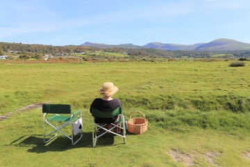 A female having a picnic and enjoying the view of the Rhinog mountains from Llandanwg, Wales, UK.