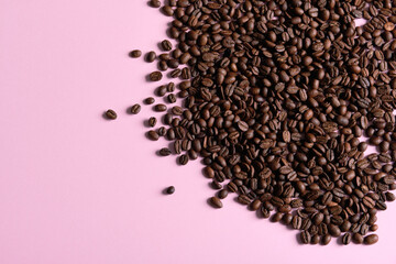 Roasted and aromatic Coffee beans on pink colored surface as background. Top view with and copy space for text. Macro photo of fresh arabica coffee beens.
