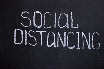 Fototapeta premium Social distance is a protective measure against Covid-19. Text on chalkboard