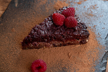 Chocolate berry piece of cake with cocoa on a black stone board. Yummy.