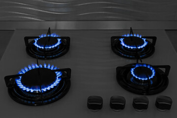 Modern gas cooktop with burning blue flames in kitchen at night