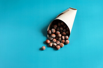 Top View of  a bag of hazelnuts in nutshell on the blue background. Natural and organic food full of vitamins. Seasonal vegetarian nutrition.