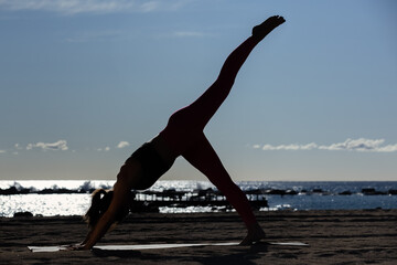 Caucasian woman doing stretching and yoga on Barceloneta beach in Barcelona