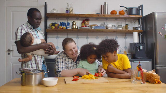 Happy Multiethnic Family In Kitchen Having Fun And Cooking Together.